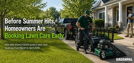 Lawn care worker unloading a mower from a trailer in front of a suburban house.