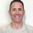 Smiling lawn care professional in a black polo shirt
