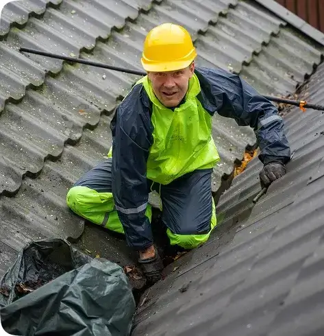 Gutter cleaning technician in safety gear clearing a rooftop gutter in Oceanside, CA