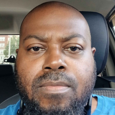 Smiling man in grey collared shirt, professional headshot
